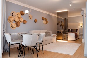 Ein modernes Wohnzimmer mit Essbereich, ausgestattet mit einer Couch, Sesseln, einem Couchtisch und einer Wand, die mit Hüten dekoriert ist.