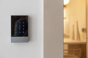 Ein an der Wand montiertes digitales Tastenfeld, vermutlich für ein Türschloss.