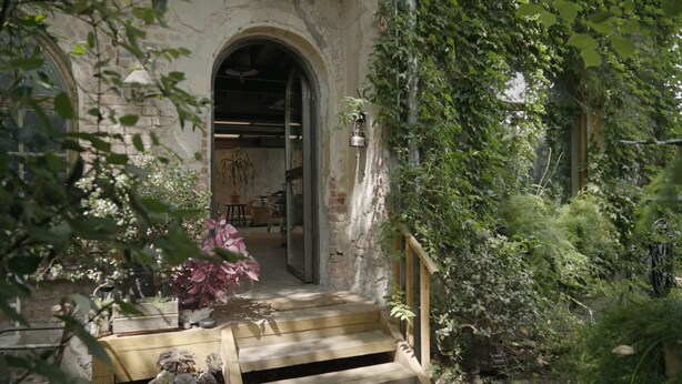 A rustic stone building with a wooden staircase leading to an interior space. - Retiro Park Industrial House (Madrid)