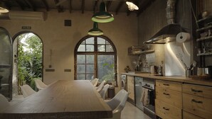 A rustic kitchen with a large wooden table, white chairs, a stove, and a sink. - Retiro Park Industrial House (Madrid)