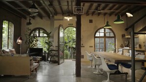 A spacious room with a long wooden table, white chairs, and a television. There are arched windows and a door labeled "SALIDA". - Retiro Park Industrial House (Madrid)
