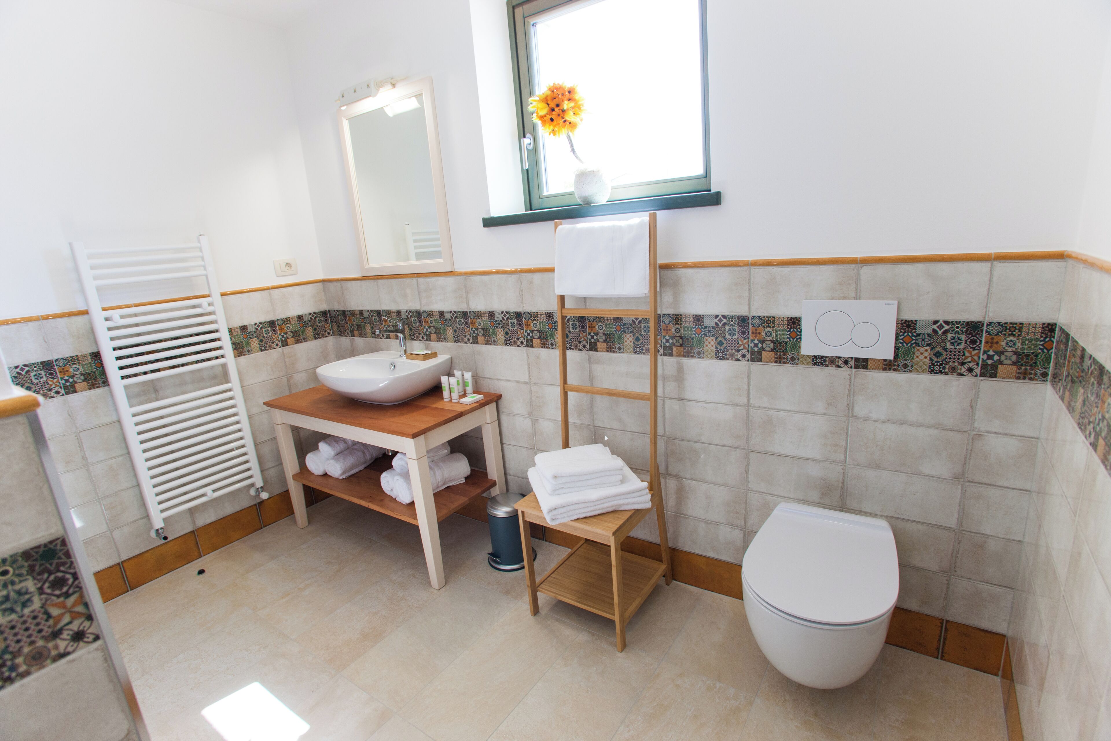 Ein Badezimmer mit Waschbecken, Spiegel, Handtuchhalter und Toilette.