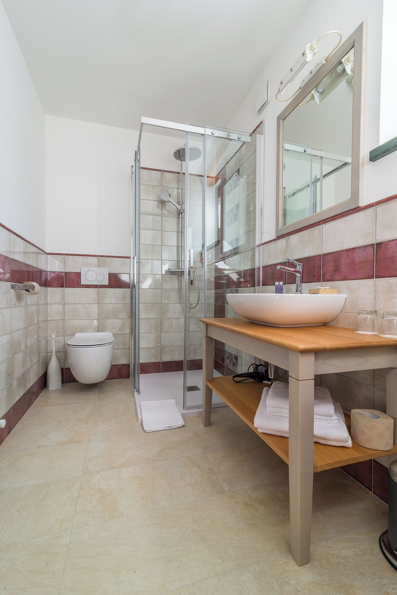 Een badkamer met een douche met glazen wanden, een witte wastafel en een spiegel erboven.