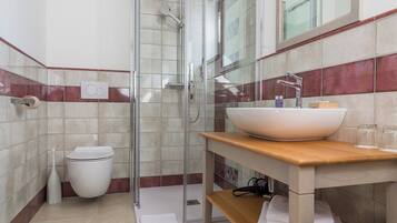 Een badkamer met een douche met glazen wanden, een witte wastafel en een spiegel erboven.