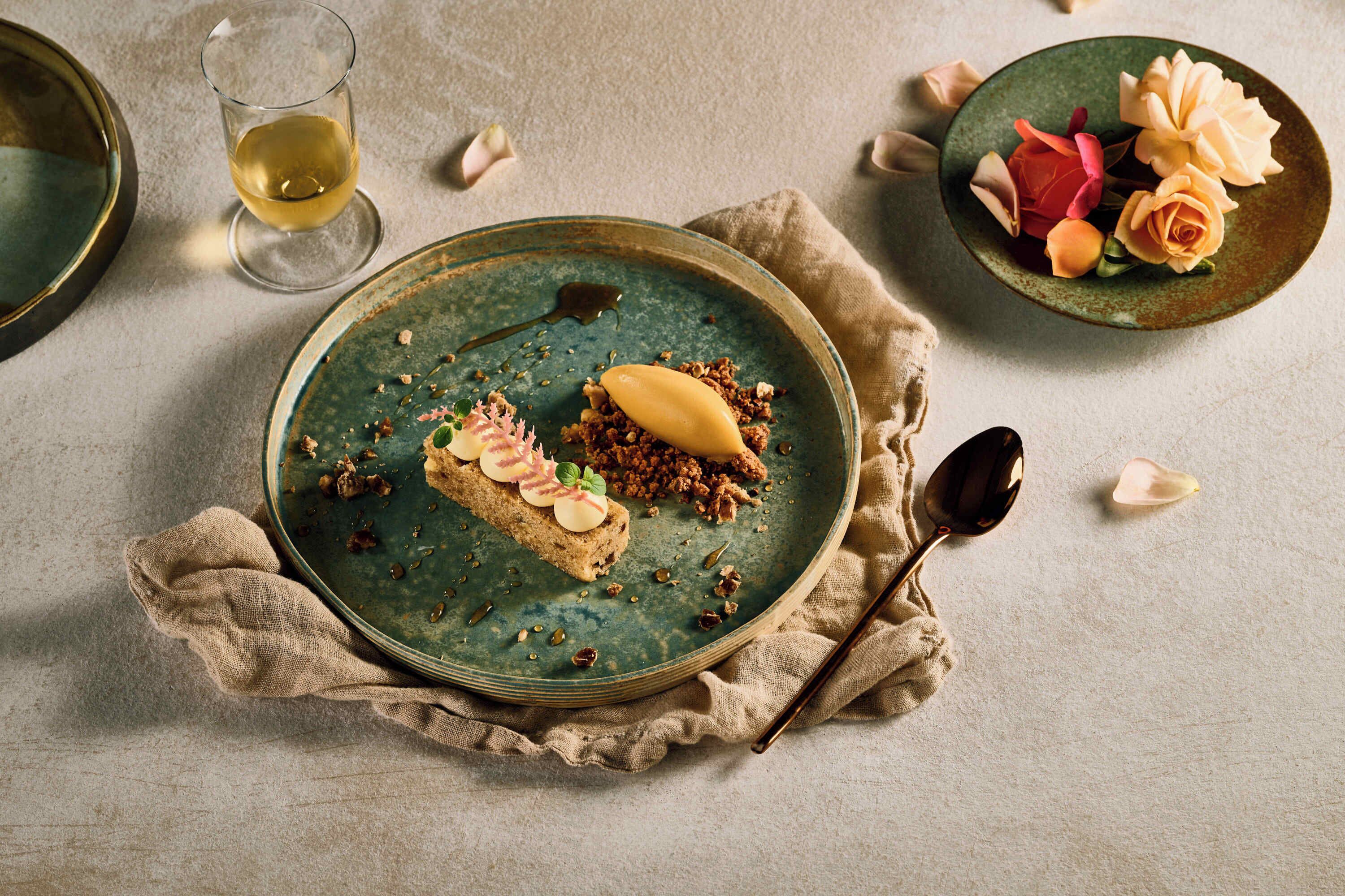 Un plato con comida y una copa de vino sobre una superficie con textura.