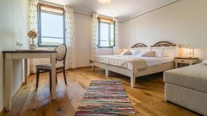 A bedroom with a bed, bedside table, chair, desk, and a window with curtains. - Hisa Krasna (Sežana)