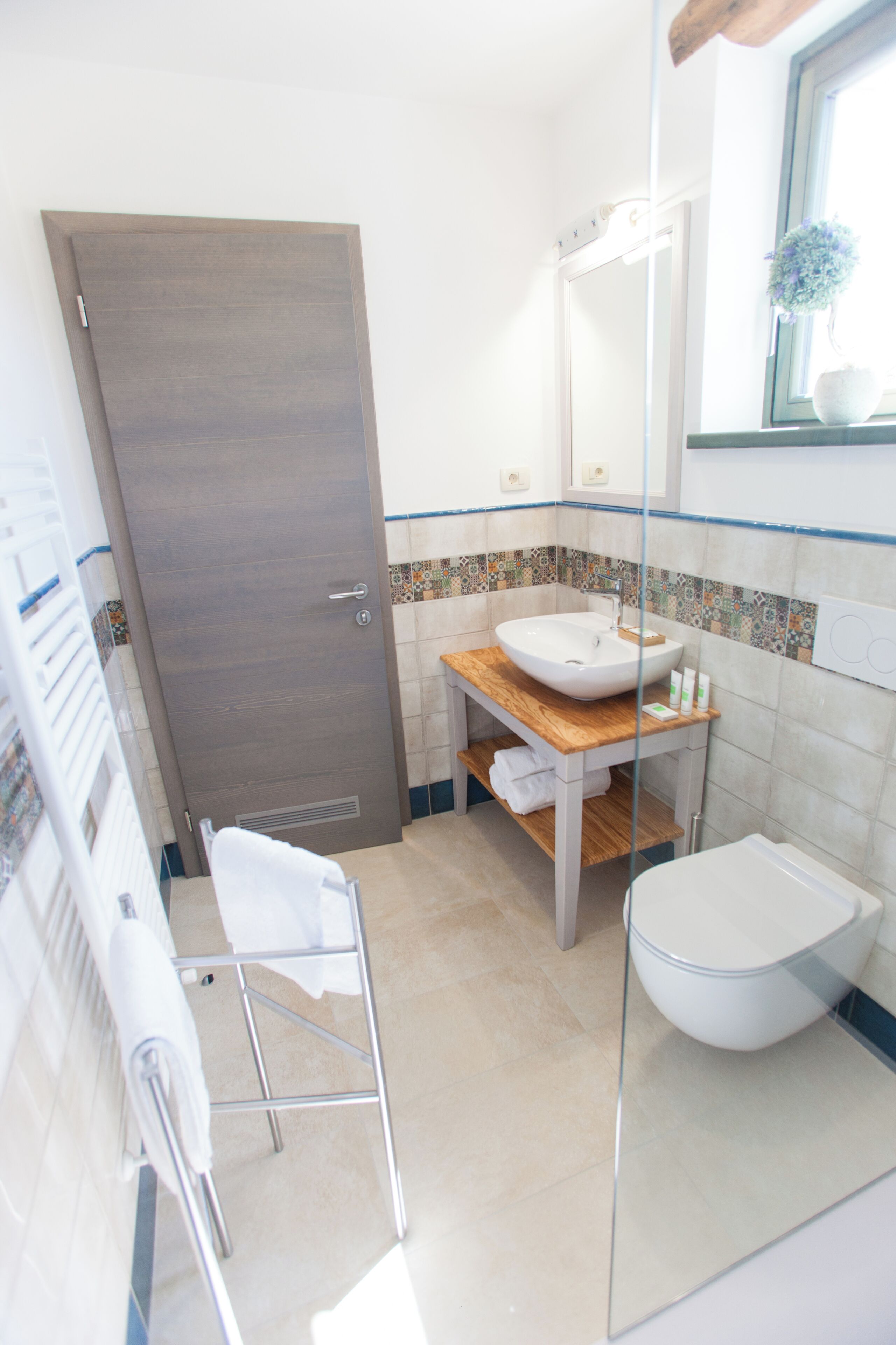 Un baño con tocador de madera, un lavabo blanco y un inodoro.