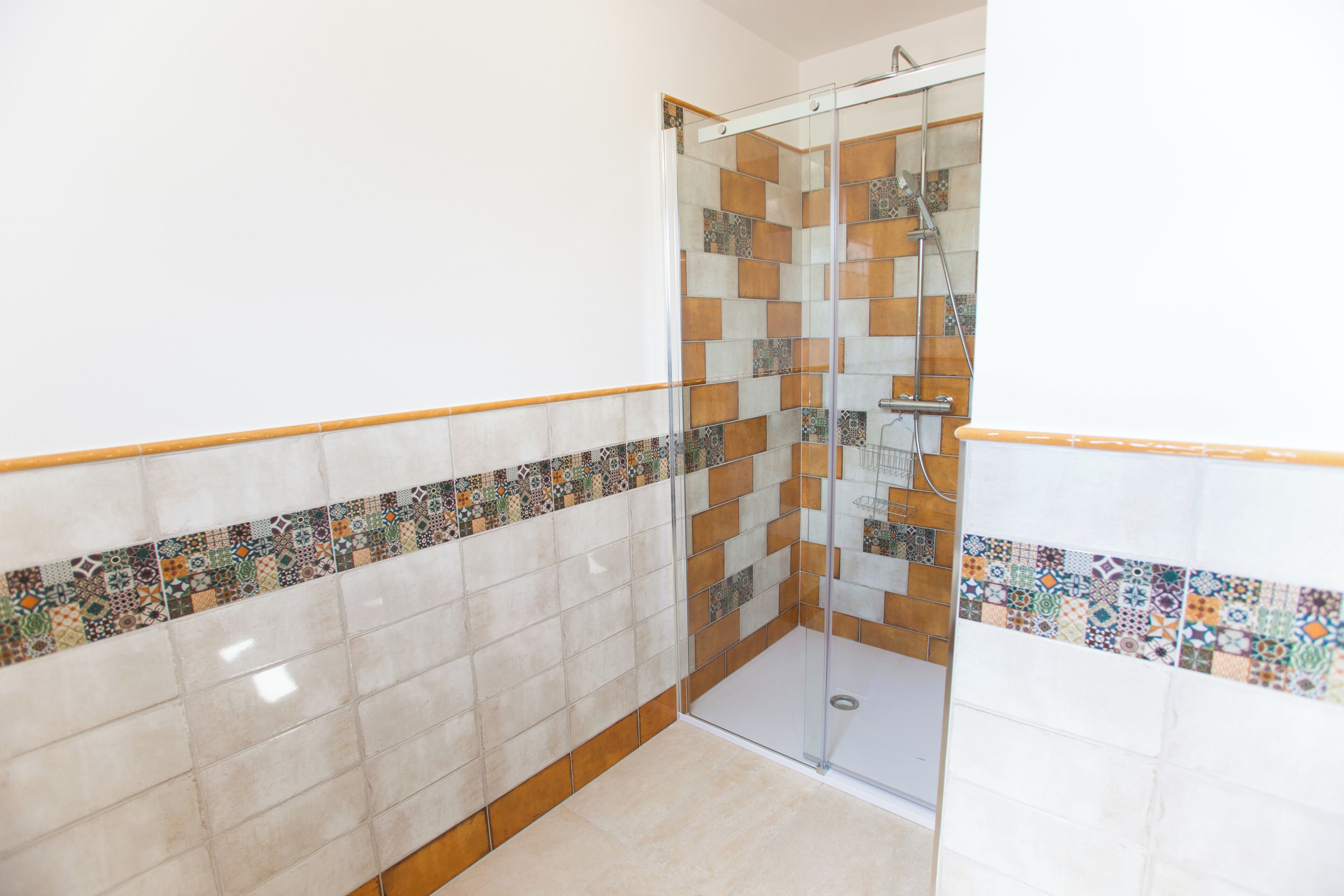 A bathroom with a shower area, tiled walls, and a glass door.