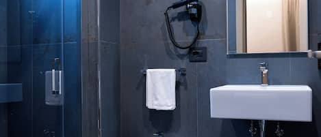 Ein modernes Badezimmer mit Duschkabine aus Glas, einem weißen Waschbecken auf Säule und einem Bidet.