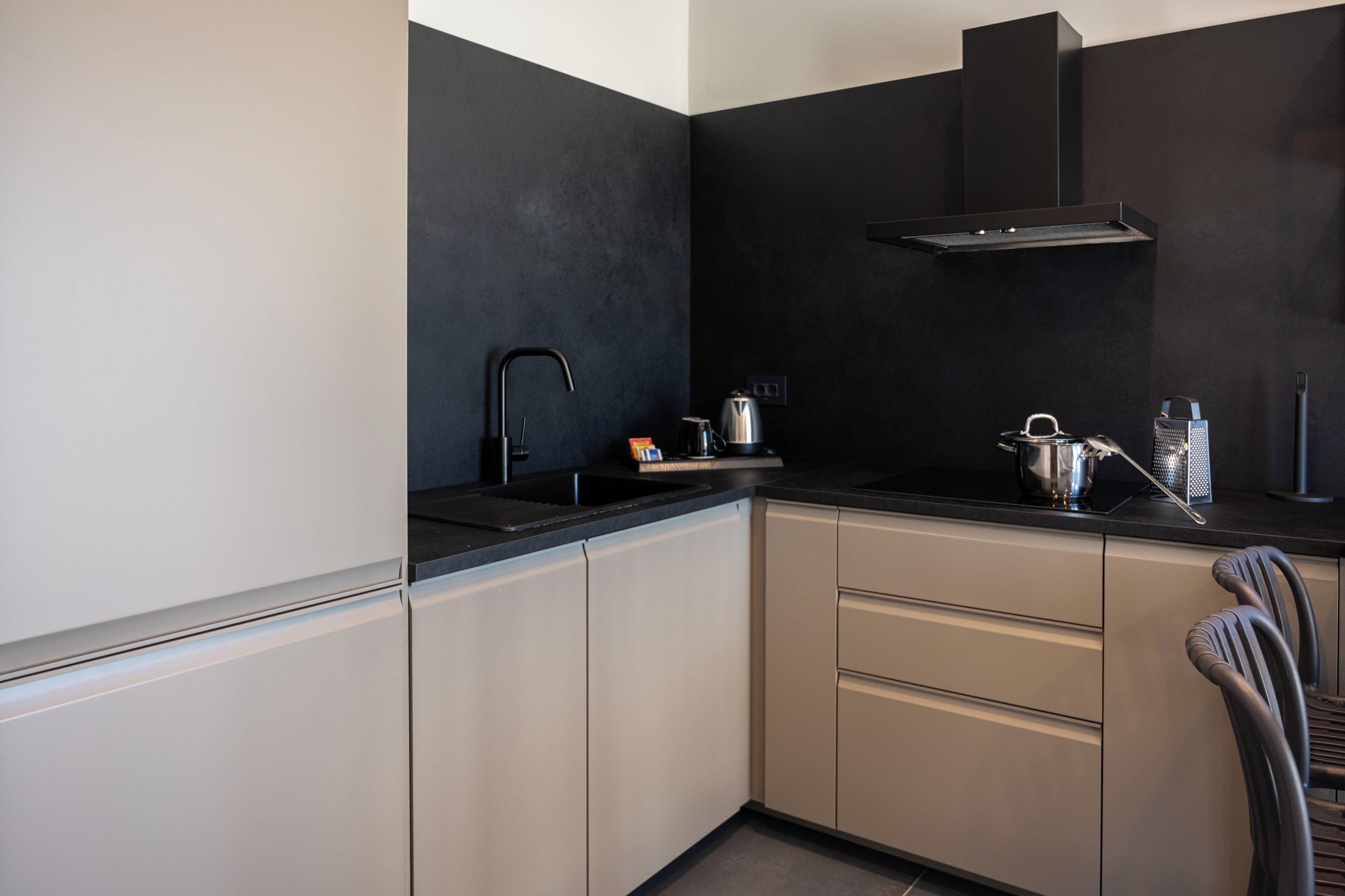 A modern kitchen with a black backsplash, stainless steel appliances, and a chair.