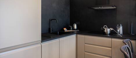 A modern kitchen with a black backsplash, stainless steel appliances, and a chair.