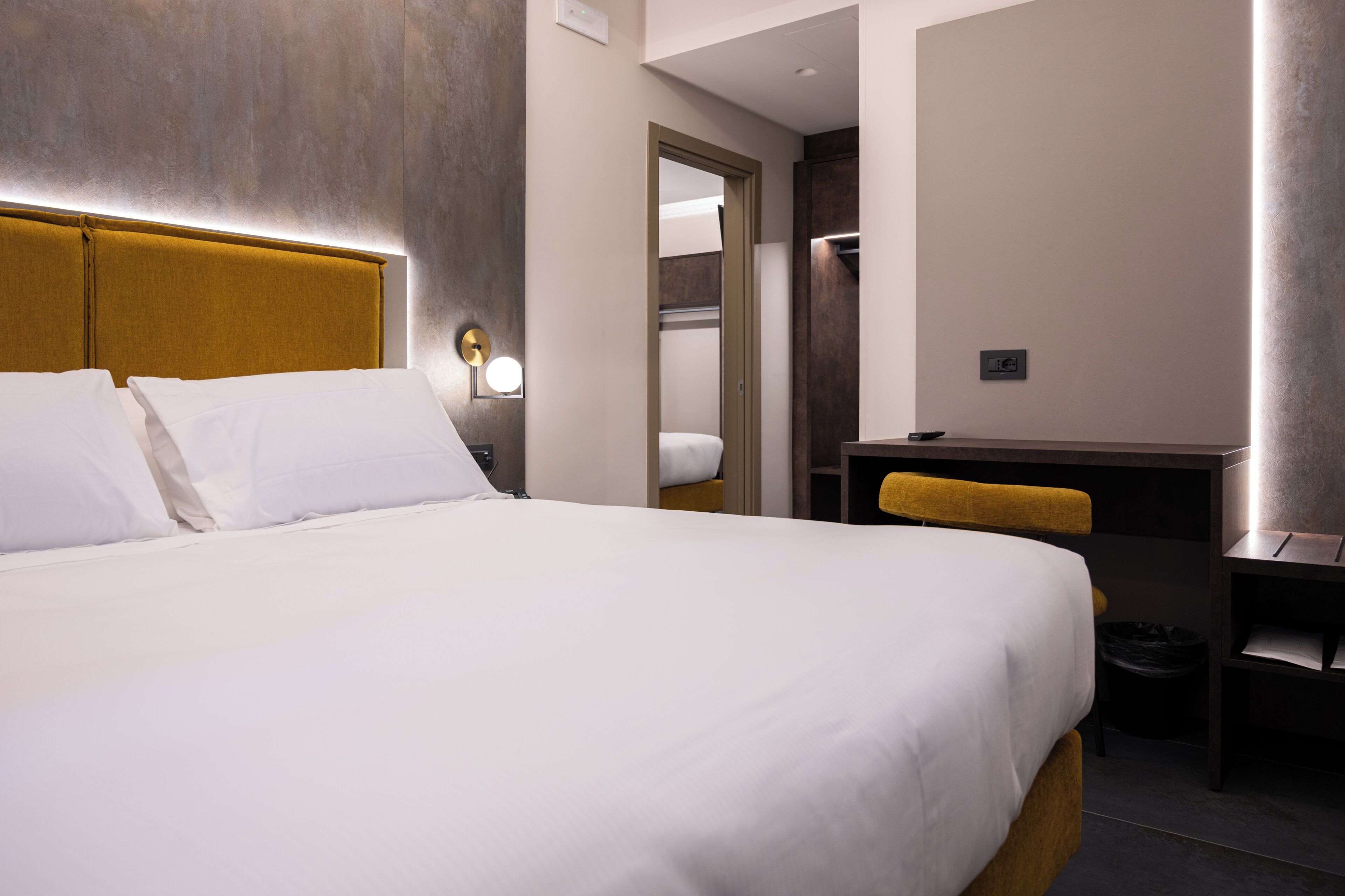 Habitación de hotel con una cama grande, un escritorio y un espejo.