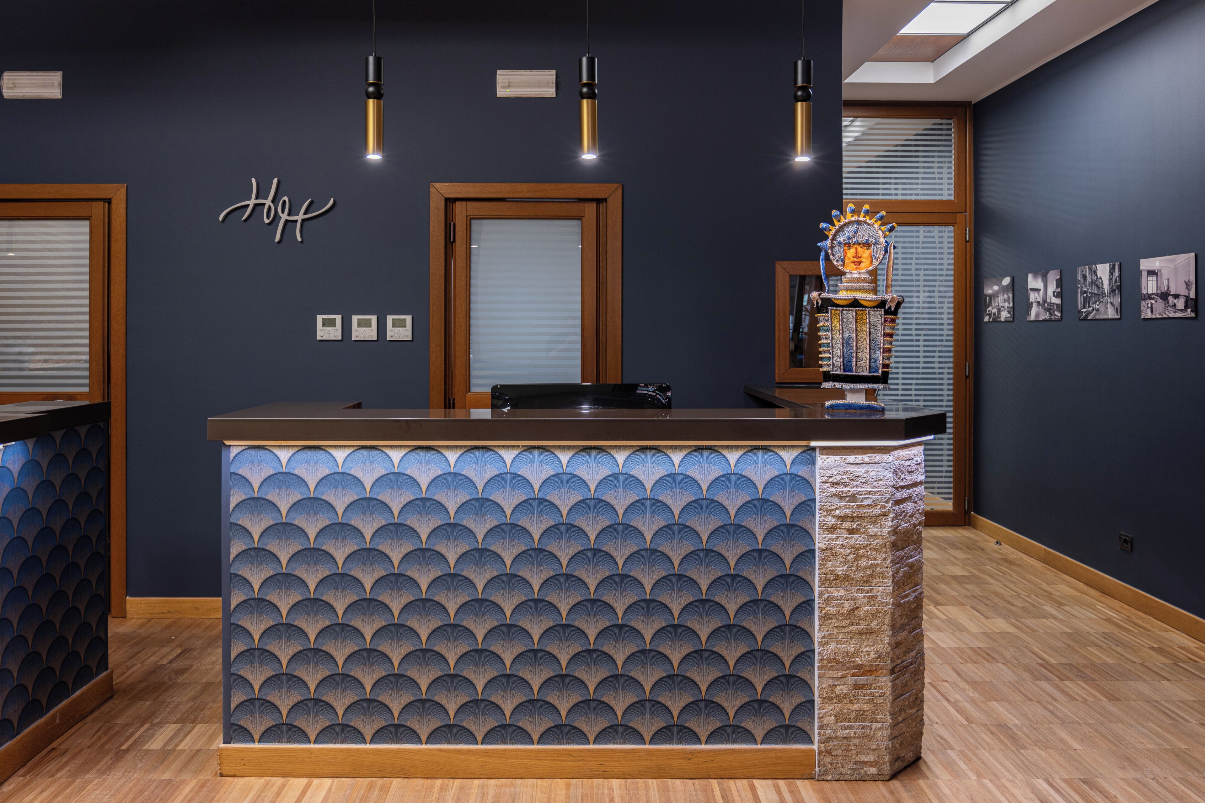 A reception desk with a patterned backdrop, a wooden floor, and a dark wall with a 'Hi' sign.