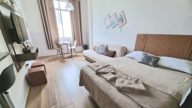 A hotel room with a bed, a desk, a chair, a TV, and a window with curtains. - Studio 325 Teresópolis - Best Location.  WATERFALLS AND GASTRONOMY (Teresópolis)