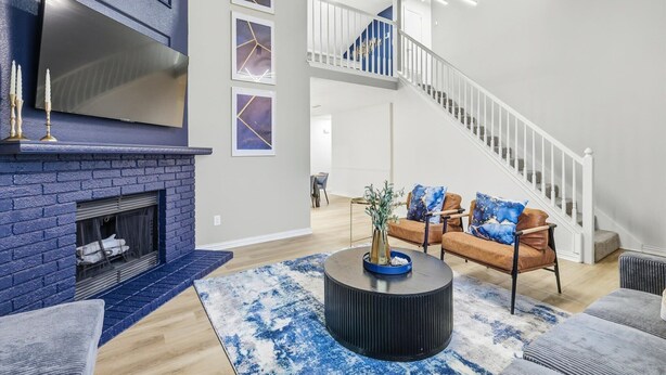 Un vaste espace de vie doté d’une cheminée, d’un escalier et d’un décor moderne.