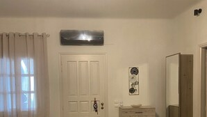 A living room with a white armchair, a wooden coffee table, a cabinet, a door, and a wall-mounted mirror. - Deppy's House (Naousa)