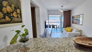 Ένα μοντέρνο σαλόνι με έναν λευκό καναπέ, ένα ξύλινο μπολ και ένα φυτό τοποθετημένο πάνω σε έναν πάγκο από γρανίτη.