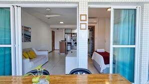 Ένα σύγχρονο σαλόνι με έναν καναπέ, ένα τραπέζι φαγητού και μια κουζίνα στο βάθος.