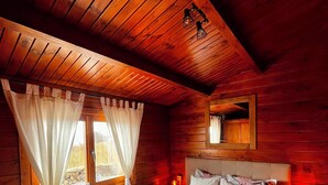 Une chambre dans une cabane en bois, avec un lit, des rideaux et une petite lampe de chevet.