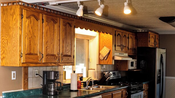 Una cucina con mobili in legno, un frigorifero in acciaio inox, un forno integrato e un angolo bar con sgabelli.