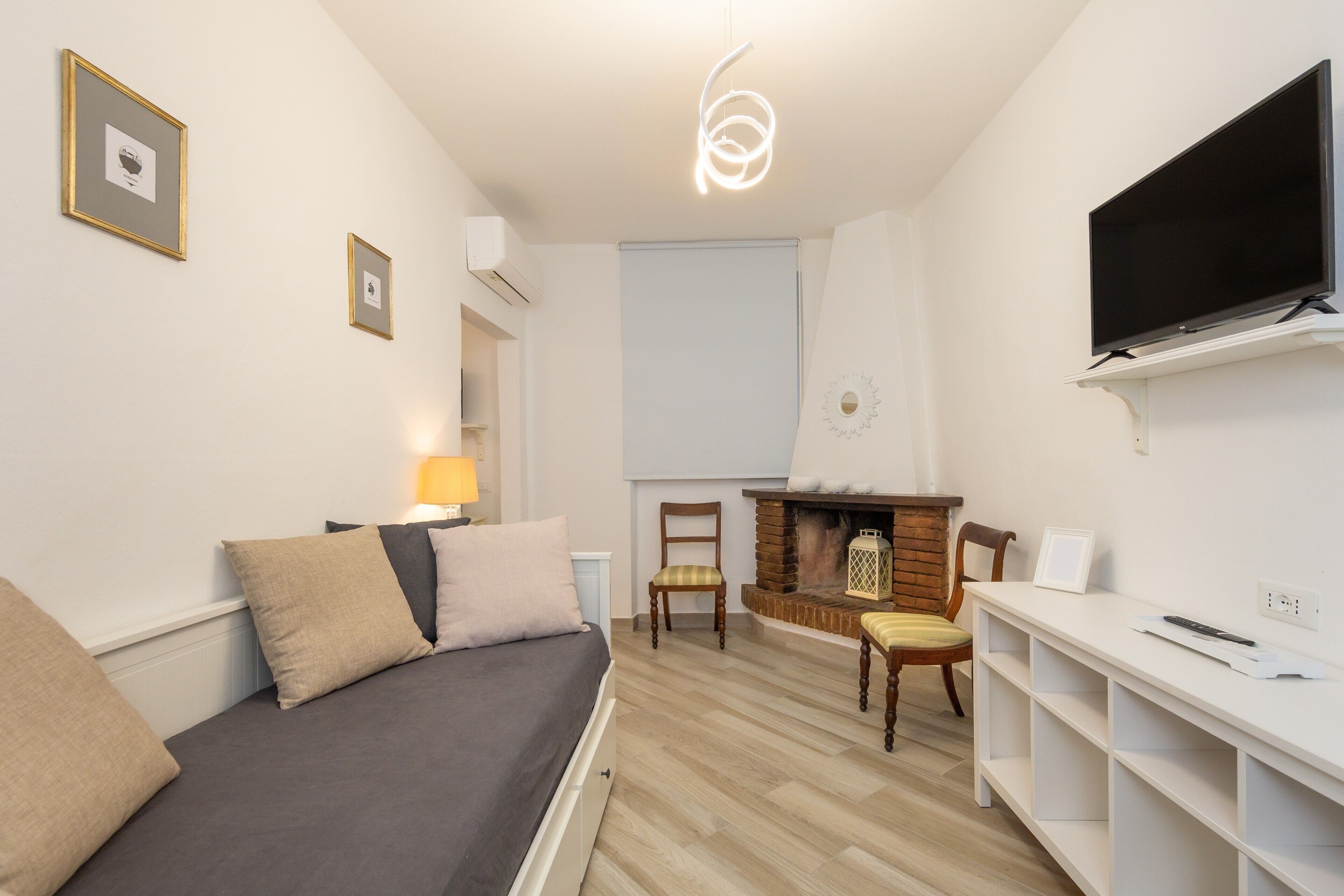A modern room with a bed, a TV, a fireplace, and a desk.