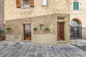 Un bâtiment en pierre avec une porte en bois, des plantes en pot et un portail en métal.