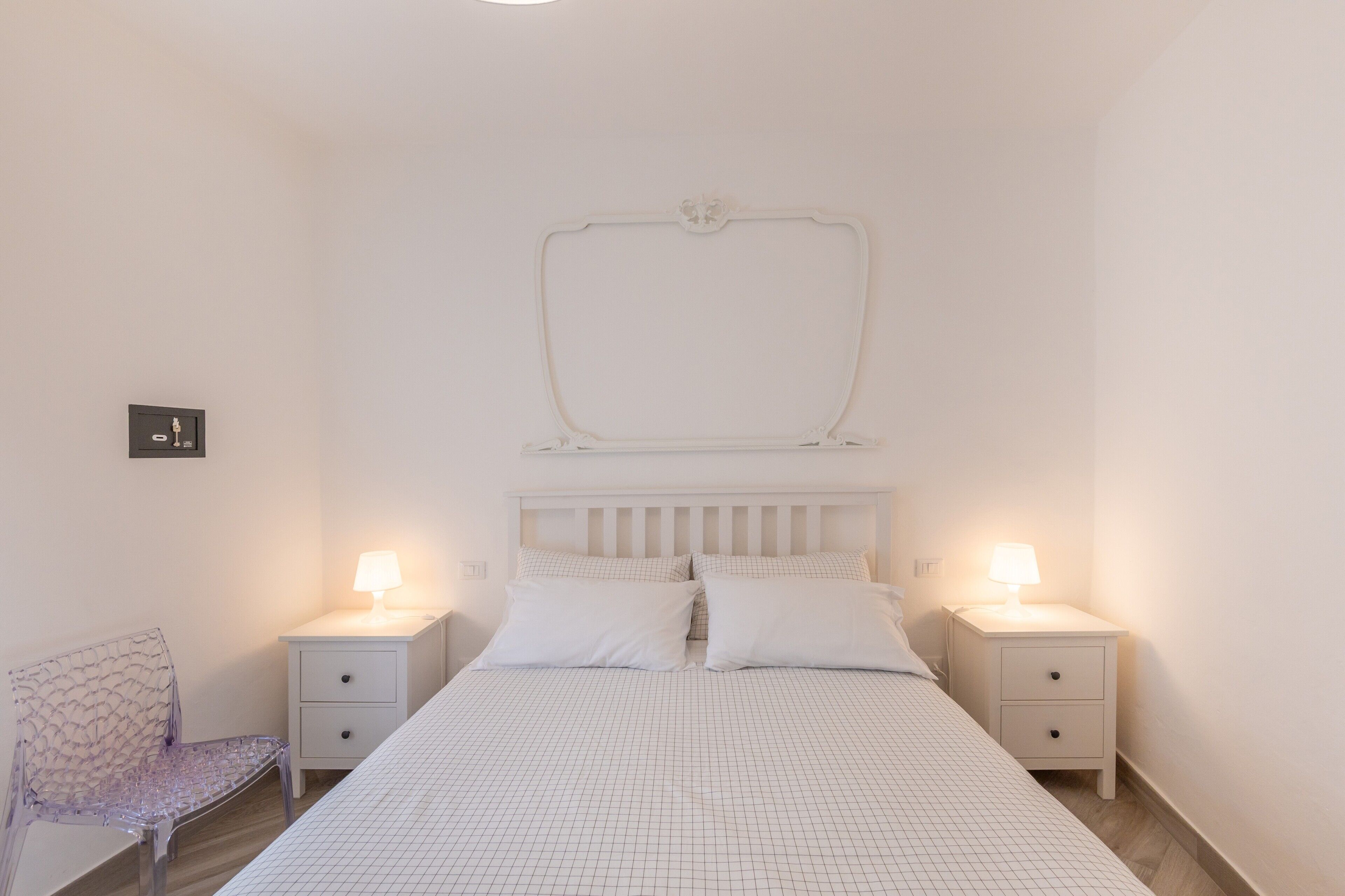 Ein Schlafzimmer mit einem Bett, zwei Nachttischen mit Lampen, einem Sessel und einer Wandleuchte.
