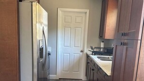 Una cocina con armarios de madera, una puerta blanca y un refrigerador de acero inoxidable.
