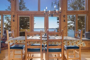 A dining area with a table and chairs, large windows, and a view of the water. - Alden East Torch Estate (Alden)