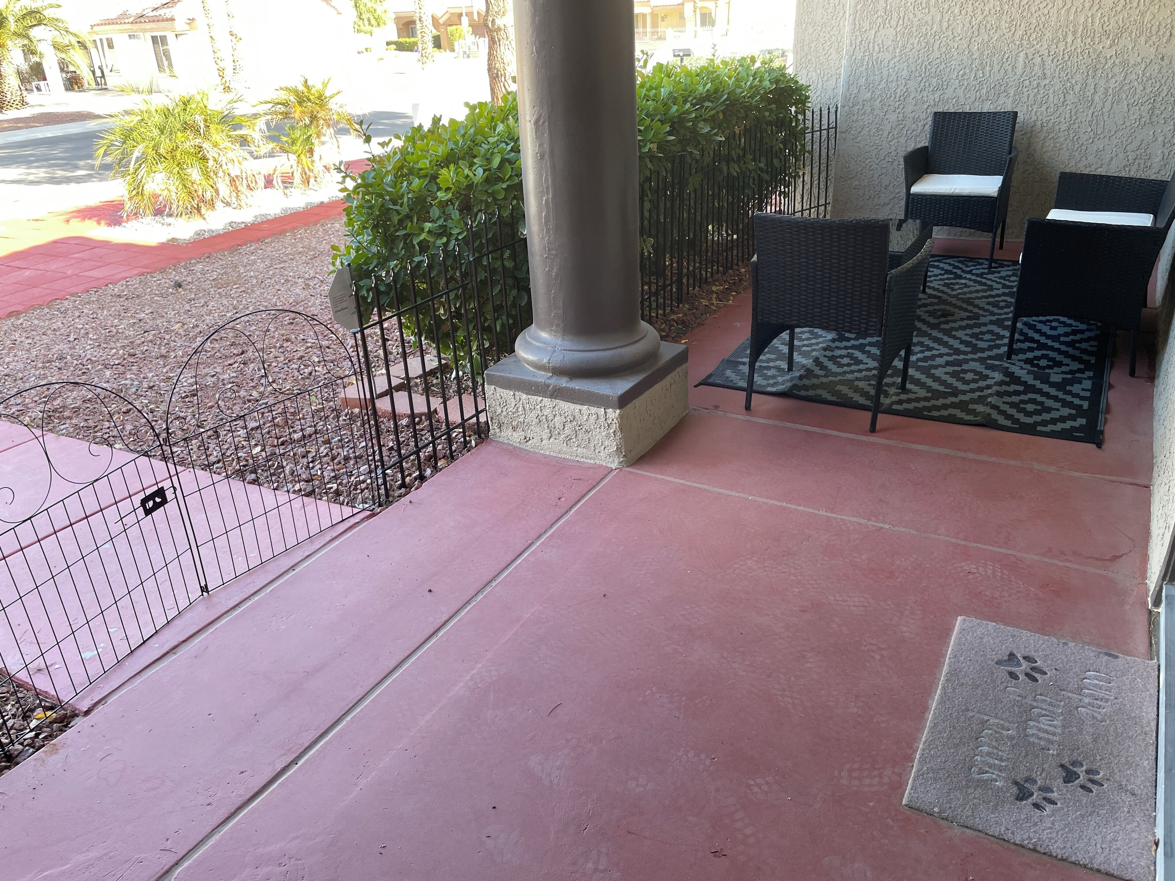 A patio area with a metal fence, a column, and outdoor furniture.