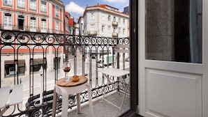 A balcony with a table and chairs, a view of buildings, and a street with vehicles. - Sweet Studio for 4 in Historical Center (Oporto)