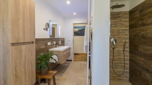 A modern bathroom with a wooden vanity, a sink, a mirror, and a shower area. - Appartement mit Zwei Schlafzimmern in Grainau (Grainau)