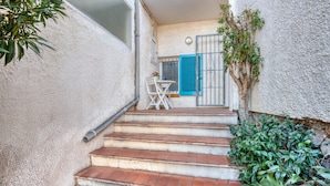 A set of outdoor stairs leading to a balcony with a table and chairs, surrounded by greenery. - MIRAVETTE: Cozy house in L’Escala near the harbor (L'Escala)