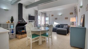 A living room with a dining table, chairs, a sofa, a television, and a fireplace. - MIRAVETTE: Cozy house in L’Escala near the harbor (L'Escala)