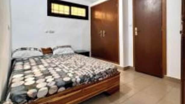 A bedroom with a bed, a ceiling fan, a window, and a door. - Apartment 100m from the beach (Aného)