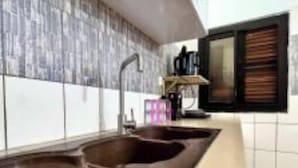 A kitchen with a large brown sink, white tiled backsplash, and a window with blinds. - Apartment 100m from the beach (Aného)