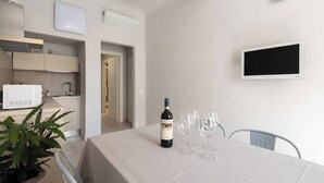 A dining area with a table set for two, a bottle of wine, and two glasses. A potted plant is on the left, and a white microwave is on the counter. - Double apartment with 2 independent entrances in the historic center of Florence (Firenze)