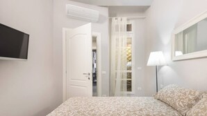 A bedroom with a bed, a TV mounted on the wall, a door leading to a closet, and a window with sheer curtains. - Double apartment with 2 independent entrances in the historic center of Florence (Firenze)