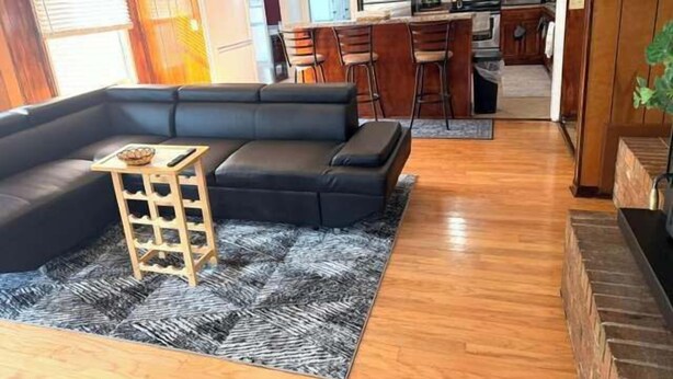 A modern living room with a black sectional sofa, a small wooden side table, and a patterned rug.