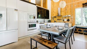 Una cocina moderna con electrodomésticos blancos, un comedor con banco y paredes de madera.