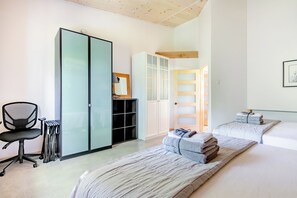 Ein modernes Schlafzimmer mit einem großen Bett, einem Schreibtisch und einem Kleiderschrank.