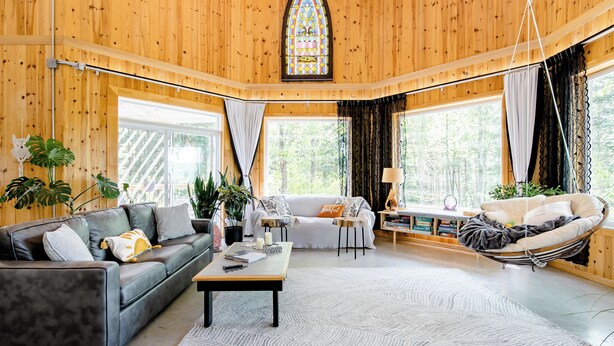 Una sala de estar acogedora con detalles de madera, un sillón colgante, un sof á y una mesa de centro.