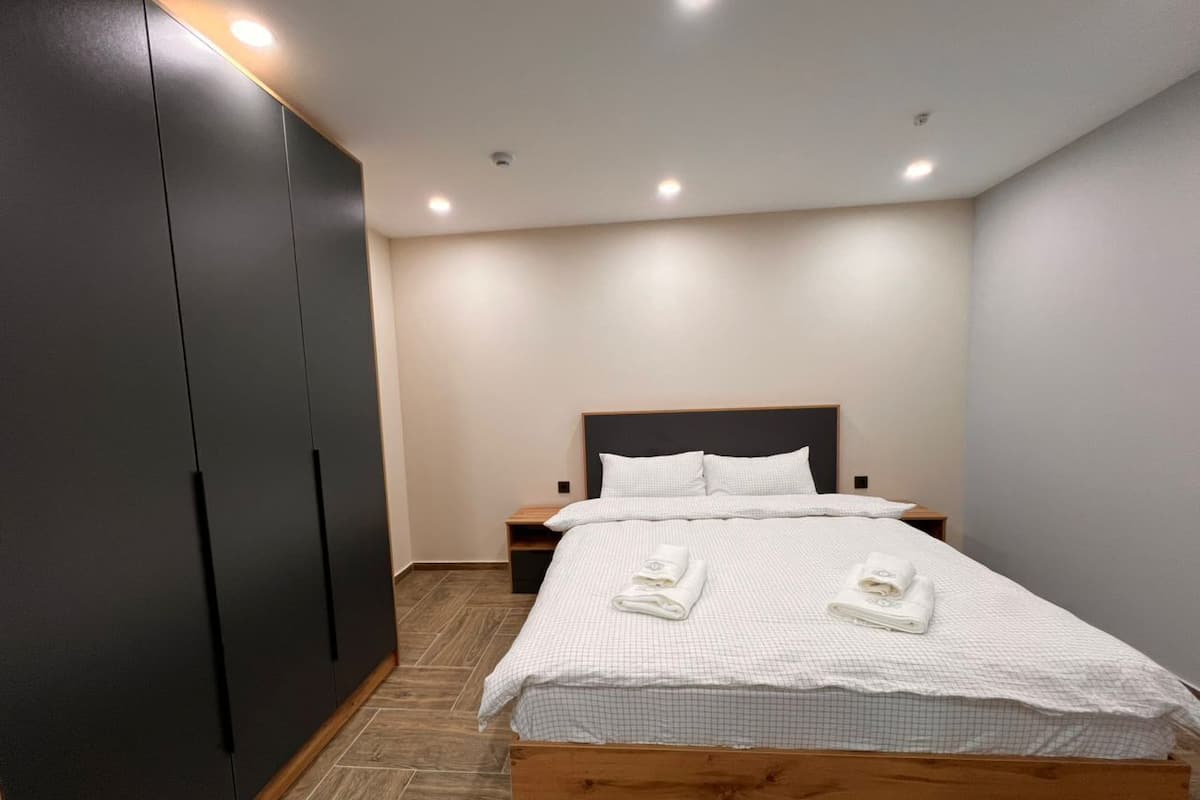 Een slaapkamer met een bed, een kledingkast en een nachtkastje.