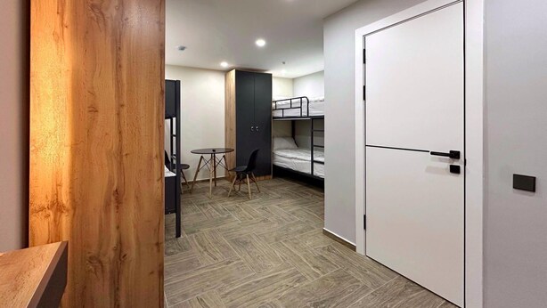 A compact room with a bunk bed, a small table with chairs, and a wooden accent wall. - Boutique Hotel 108 (Bishkek)