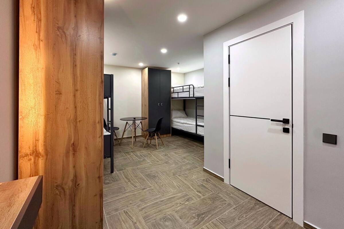 Een compacte kamer met een stapelbed, een klein tafeltje met stoelen en een wand van hout.