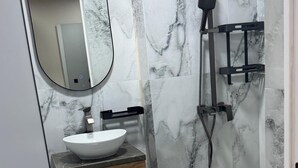 A bathroom with a white sink, a mirror, and a shower area. - Boutique Hotel 108 (Bishkek)