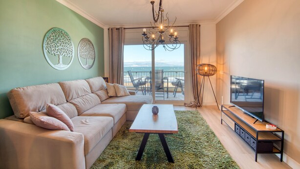 Una sala de estar moderna con un sofá, una mesa de centro, un televisor y vistas al océano.
