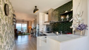 Una cocina moderna con una isla central, un comedor con vistas y una pared decorativa con un reloj.