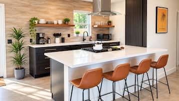 Una cocina moderna con una isla grande, taburetes de bar y vistas al exterior.