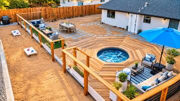 Ein Garten mit Whirlpool, Sitzgelegenheit im Freien und einer Holzterrasse.